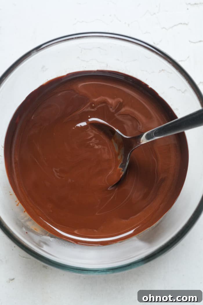 Smooth and creamy melted chocolate in a bowl, ready for dipping fresh blueberries.