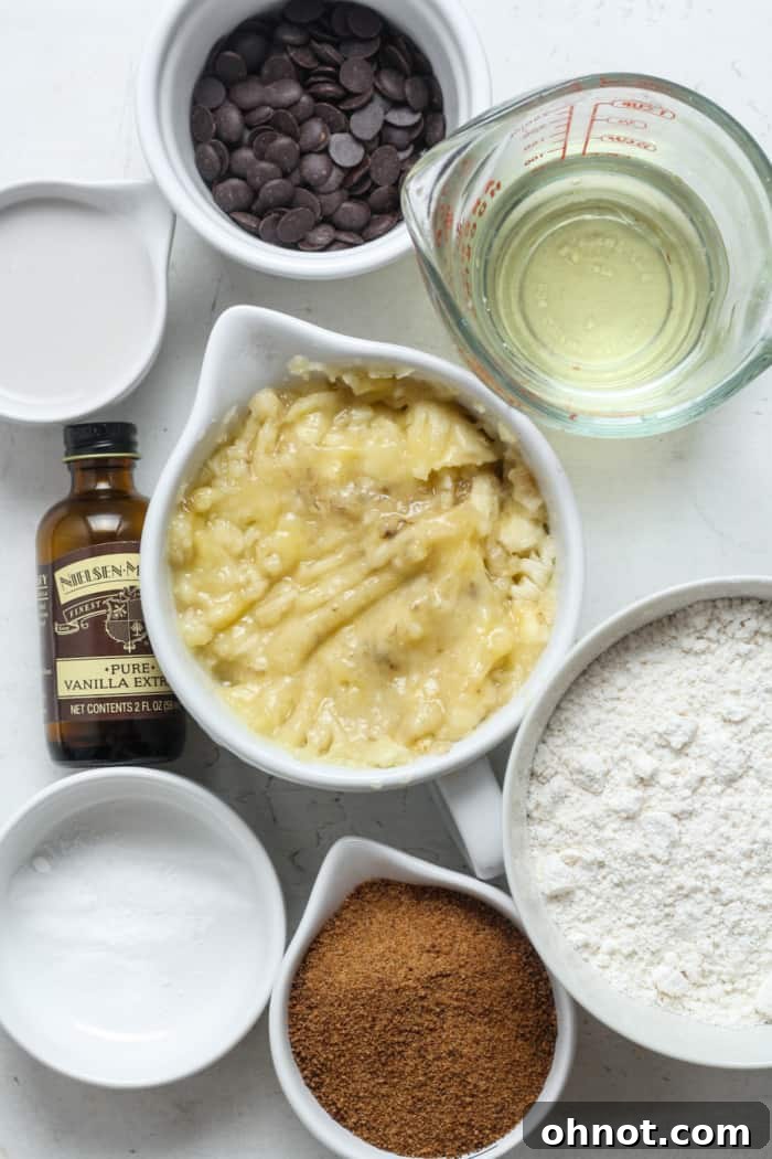 A bowl filled with mashed ripe bananas, next to other wet ingredients, ready to be mixed for the banana bread.