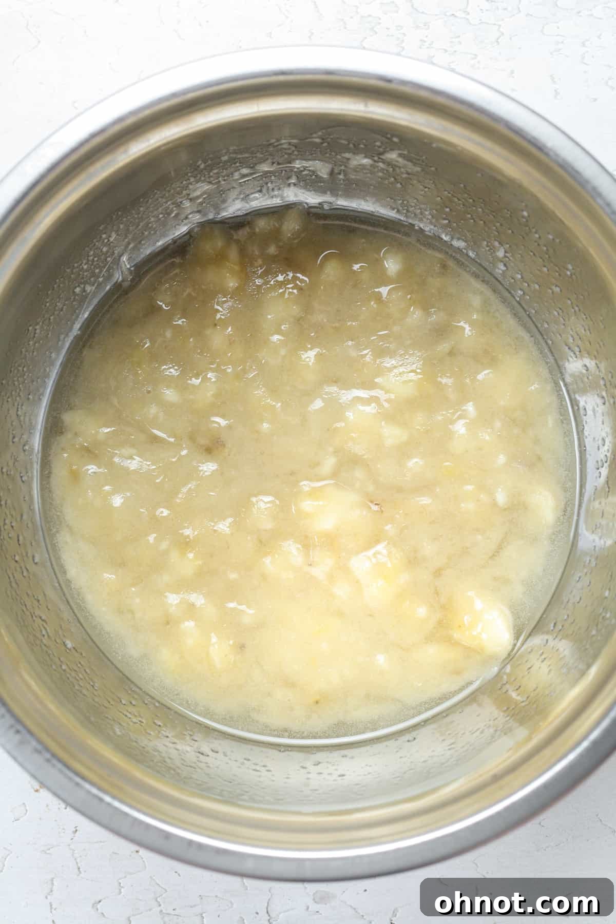 The creamy, well-combined mixture of mashed bananas and wet ingredients in a bowl.