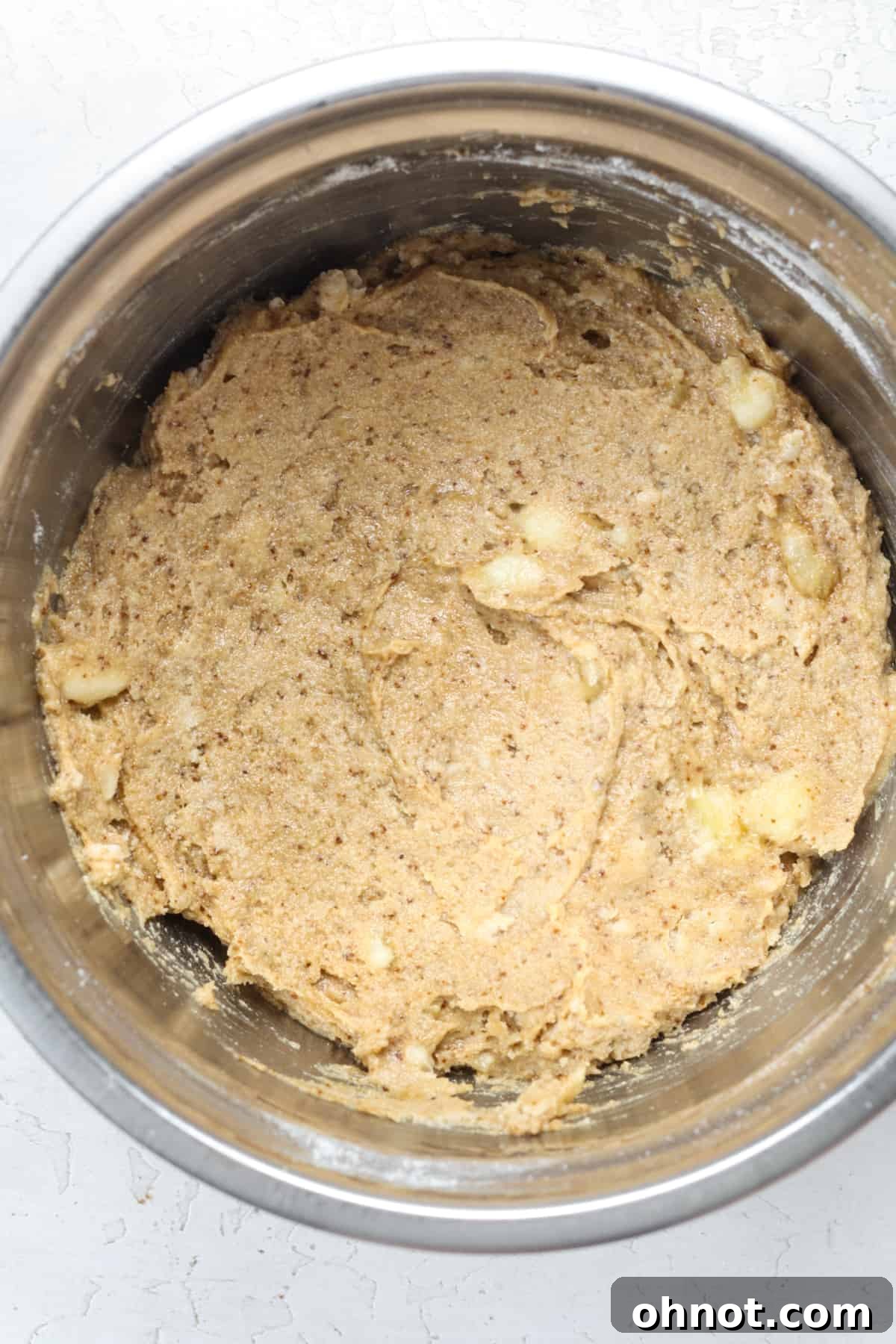 Thick banana bread dough in a bowl, showing its readiness for the next step.