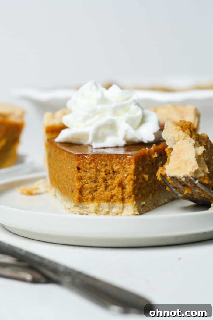 A beautifully baked gluten free pumpkin pie, golden brown crust with a smooth orange filling, ready to be sliced.