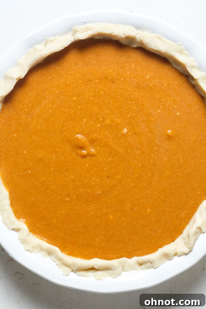 Unbaked pumpkin pie with filling poured into the crust, ready for the oven.
