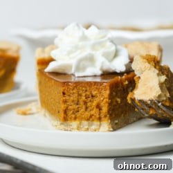 A beautifully sliced gluten free pumpkin pie on a serving board with a whole pie in the background, ready for a holiday feast.