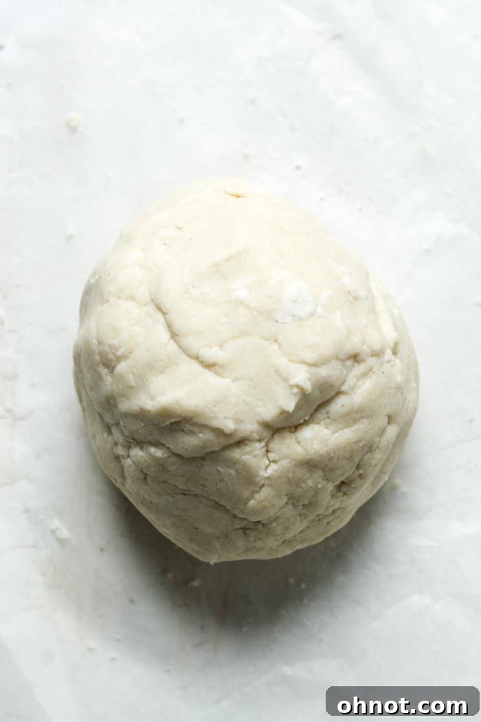 A ball of prepared pie dough wrapped in plastic, ready for chilling.