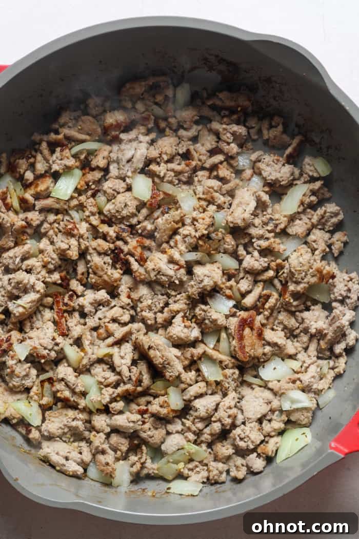 Sautéing ground turkey and chopped onion together in a skillet for the Healthy Hamburger Helper, adding aromatic flavor.