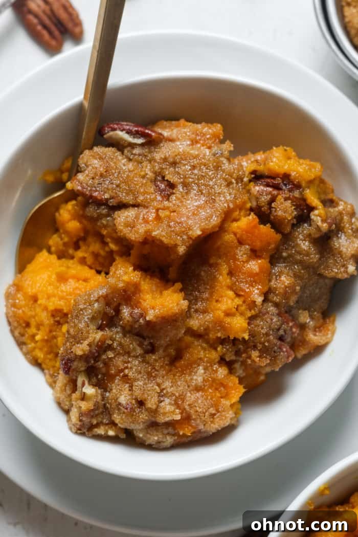 A golden brown gluten-free sweet potato casserole topped with crunchy pecans, ready to be served from a baking dish.