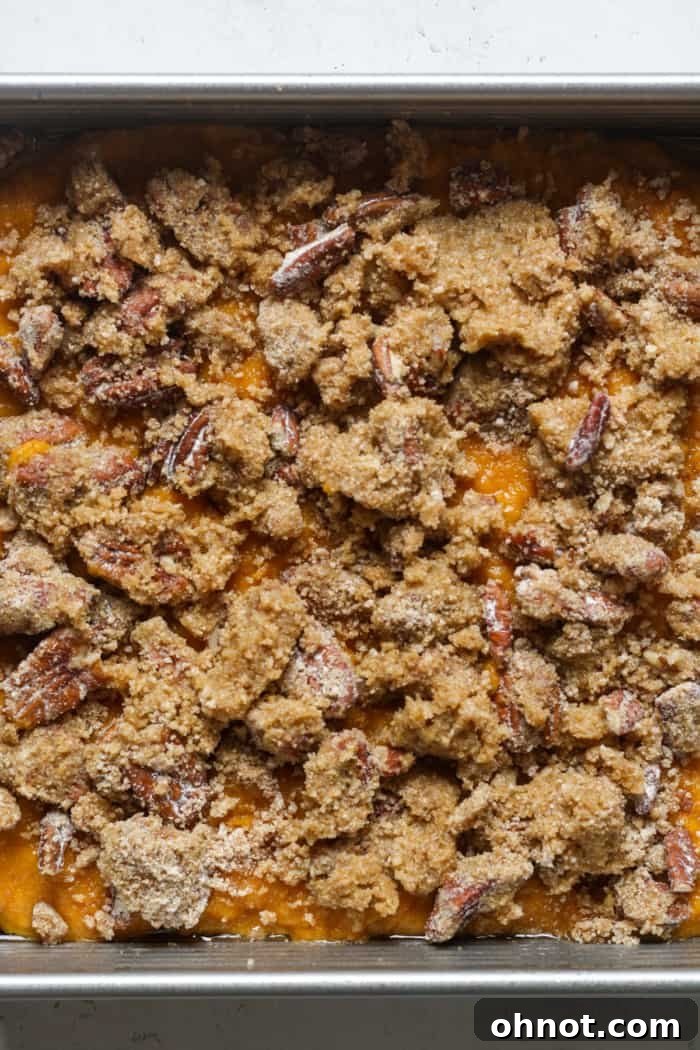 Unbaked gluten-free sweet potato casserole with the pecan topping evenly spread over the sweet potato layer.