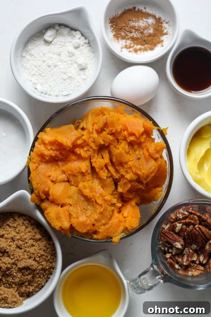 Fresh sweet potatoes, a bowl of chopped pecans, and other raw ingredients laid out on a kitchen surface for making the casserole.