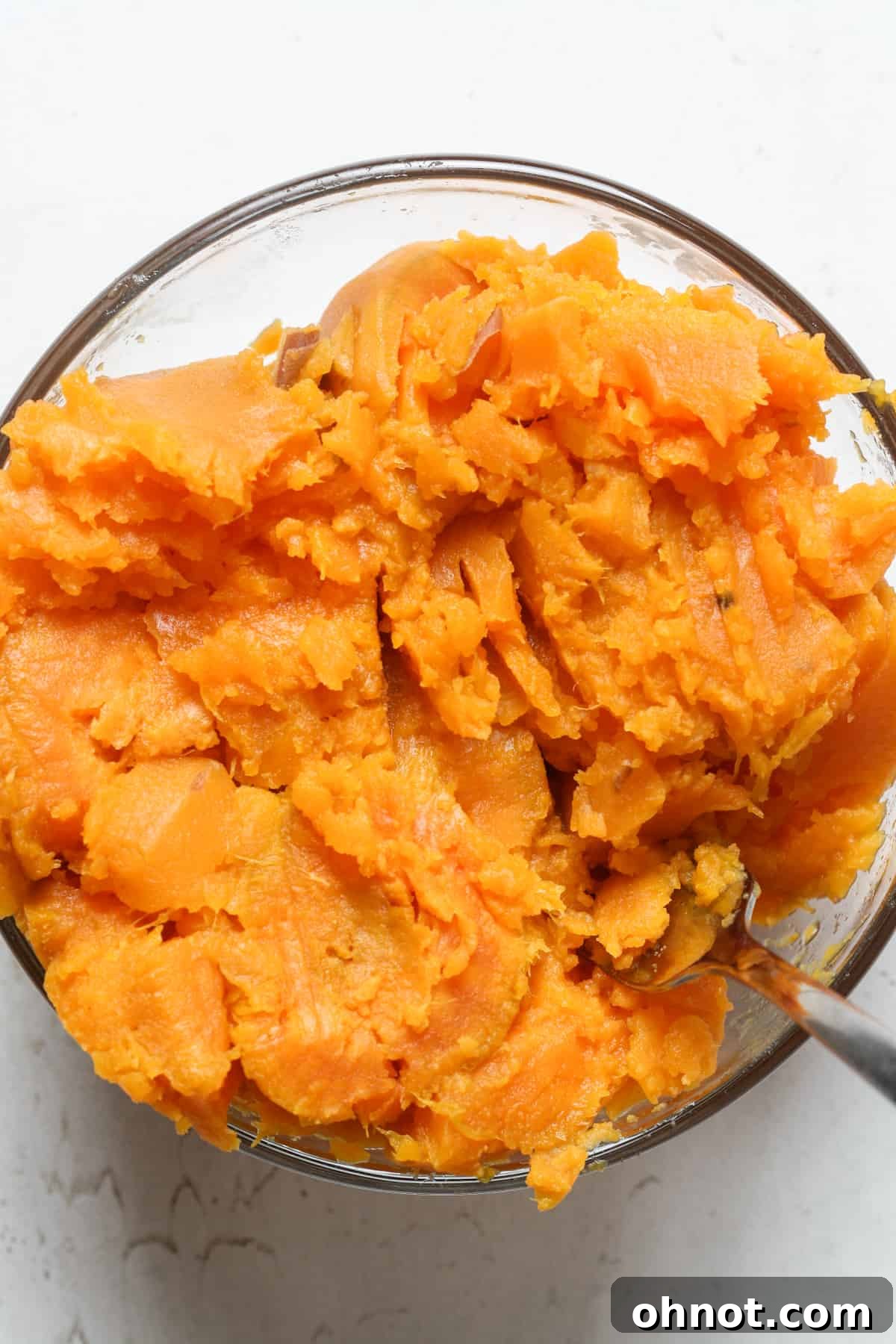 Close-up of freshly mashed sweet potato in a bowl, showing its smooth texture.