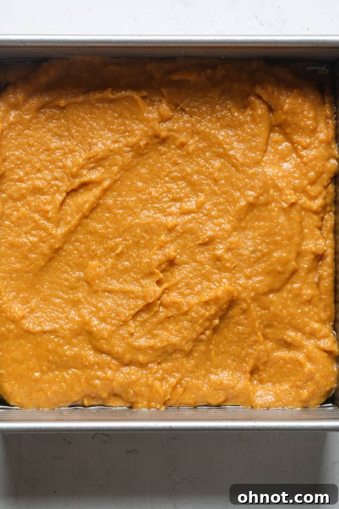 The smooth sweet potato filling spread evenly in a greased baking pan.