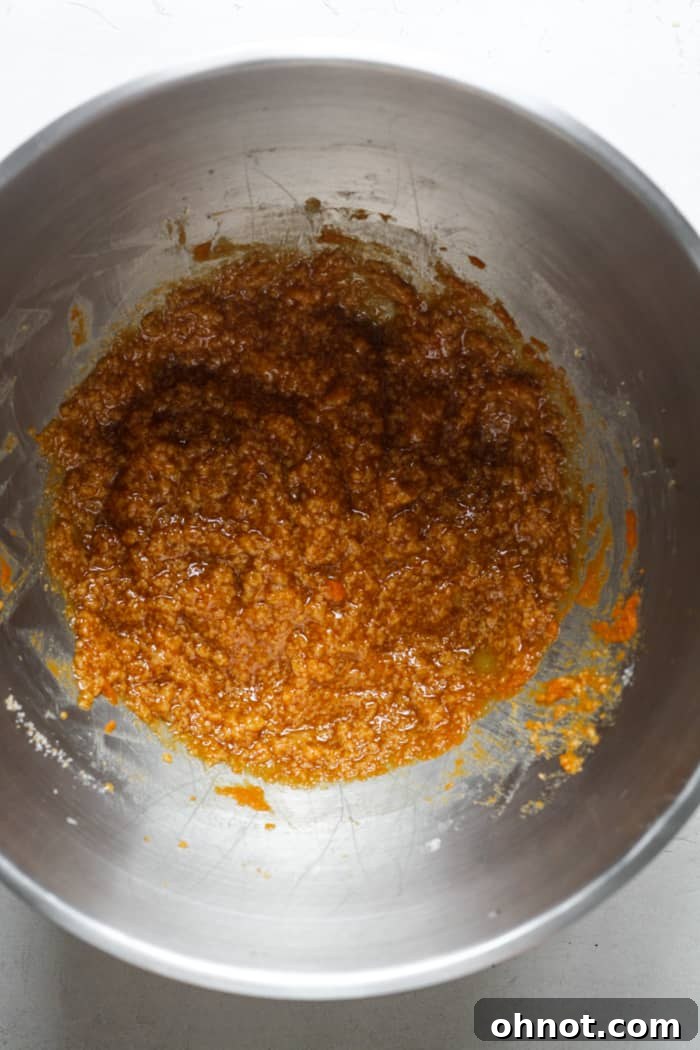 Creamy orange pumpkin dough in a mixing bowl after wet ingredients have been added.