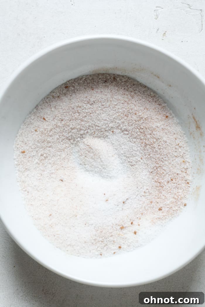 Granulated sugar mixed with pumpkin pie spice in a shallow bowl, ready for coating cookies.
