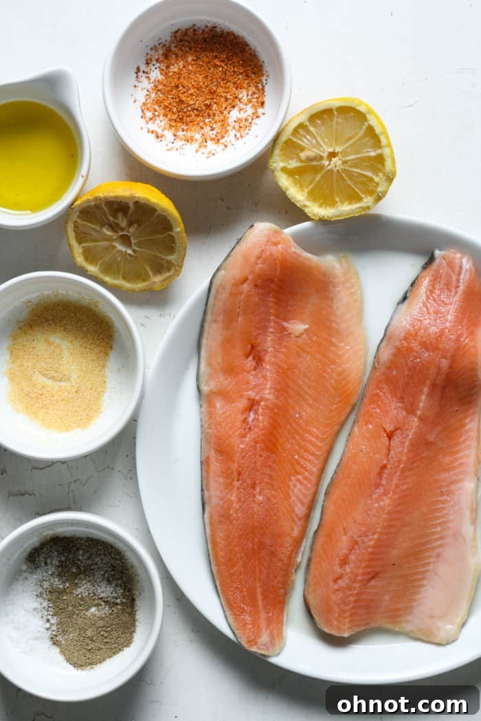 Fresh rainbow trout fillets laid out with lemon, olive oil, and various spices.