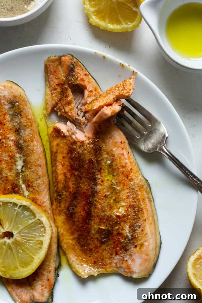 Close-up of flaky, baked rainbow trout on a plate, ready to be enjoyed.