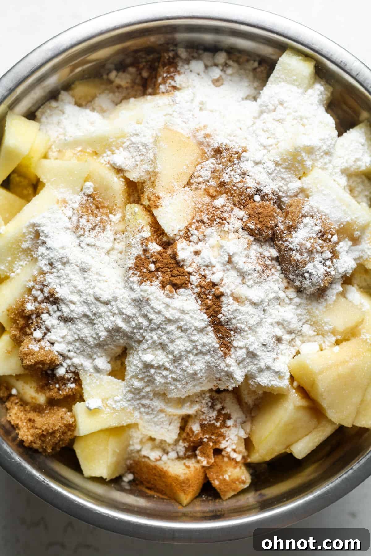 Sliced apples, flour, and cinnamon in a large mixing bowl.