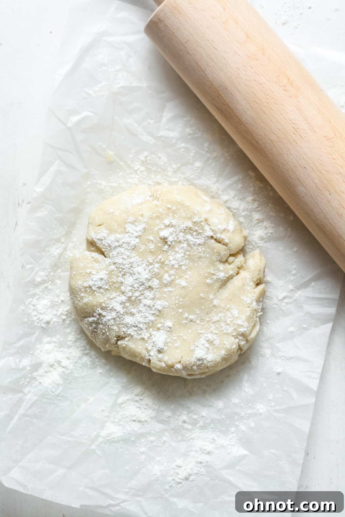 Disc of pie dough being rolled out with a rolling pin.