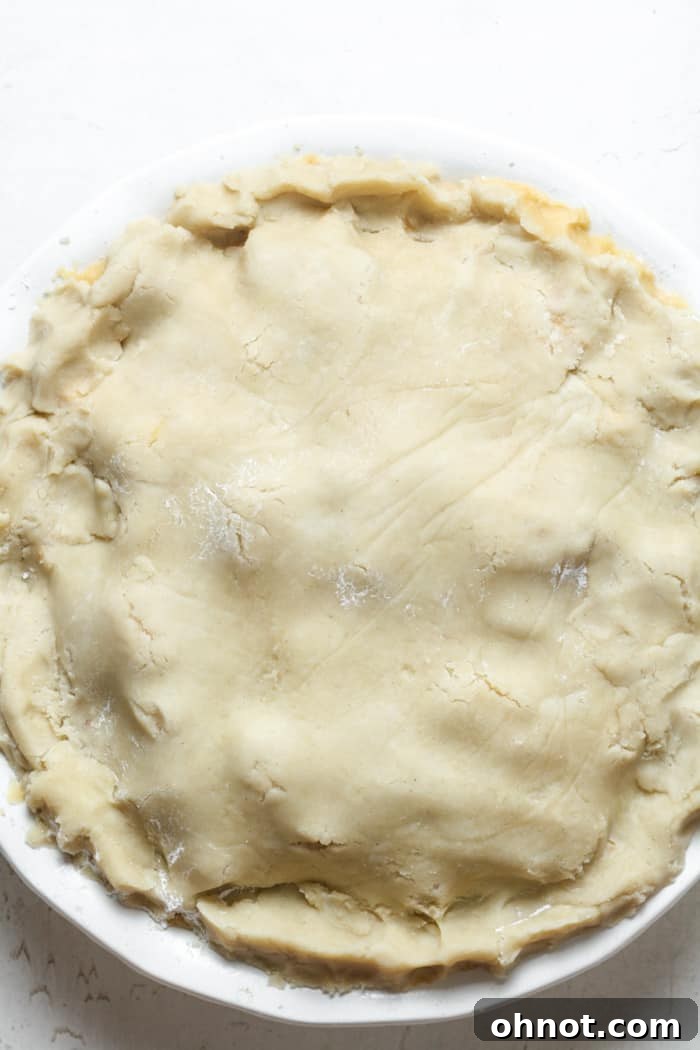Unbaked apple pie with crimped edges and a vent slit.