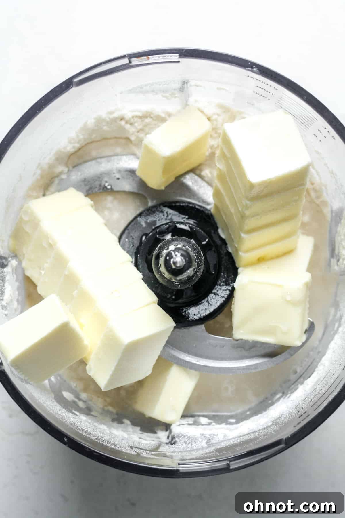 Flour, butter, and water combining in a food processor.