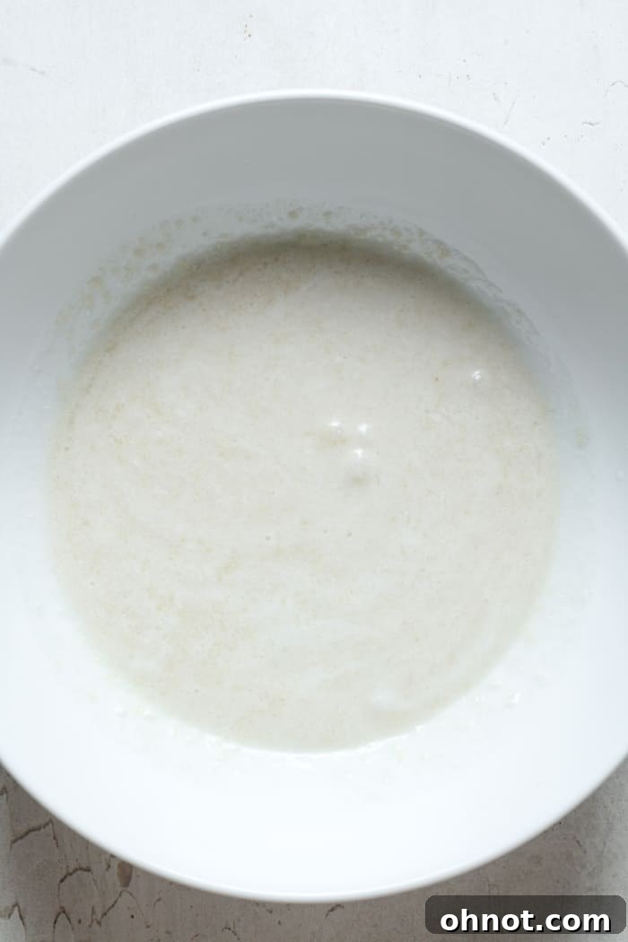 Milky substance in bowl being stirred, representing the combined wet ingredients for vegan donuts.