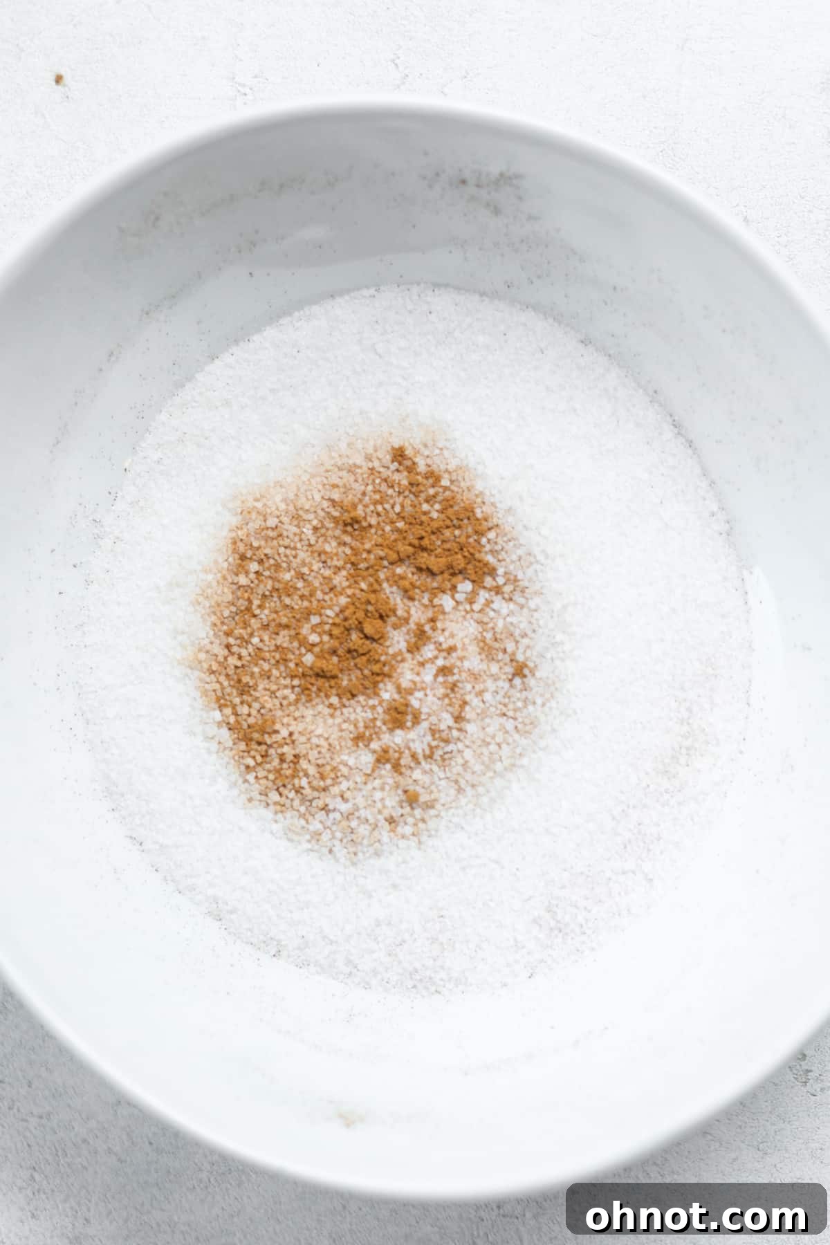 Bowl filled with mixed cinnamon and sugar, ready for coating the vegan donuts.