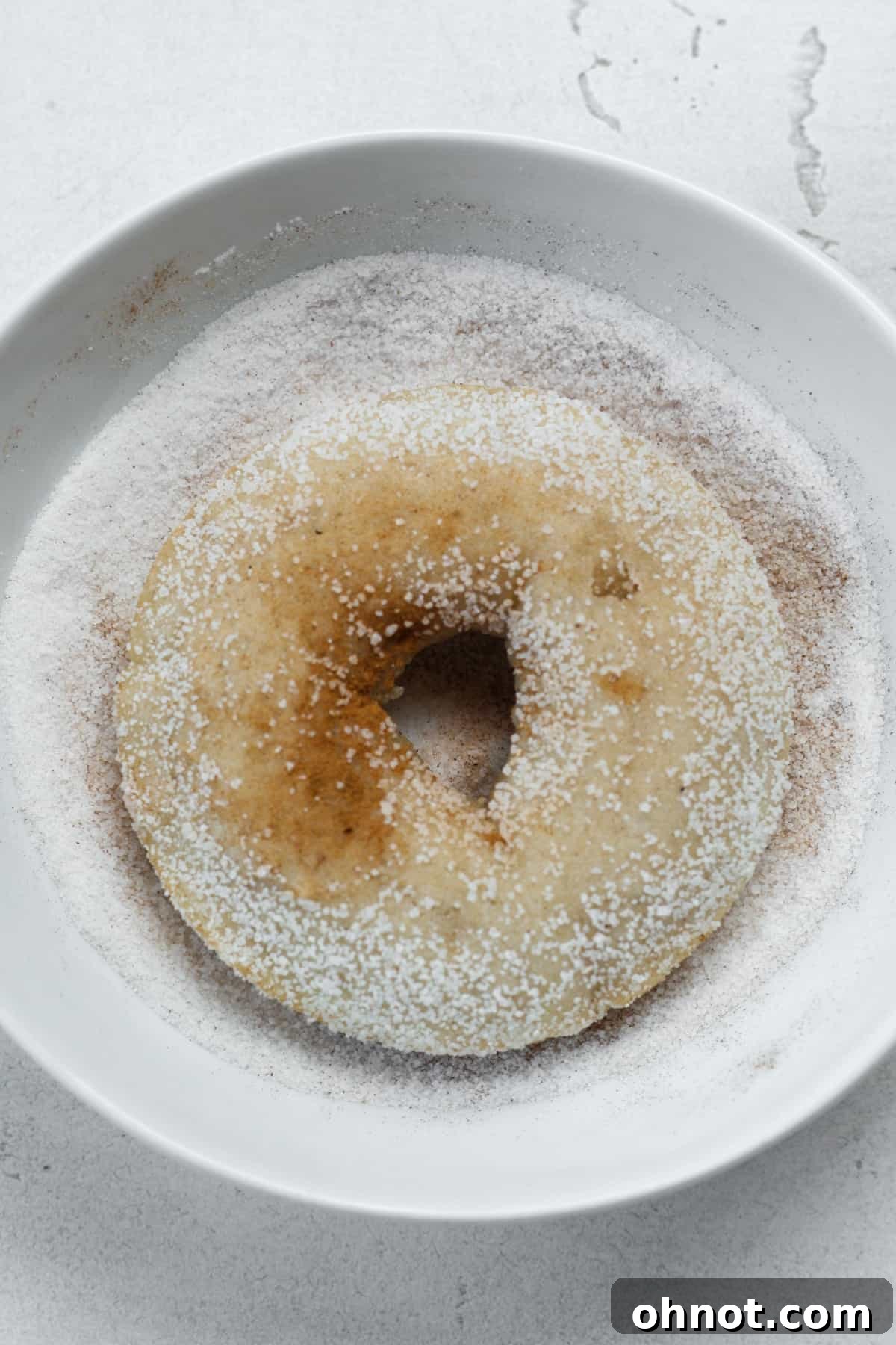 A freshly coated vegan donut with cinnamon sugar, ready to be enjoyed.