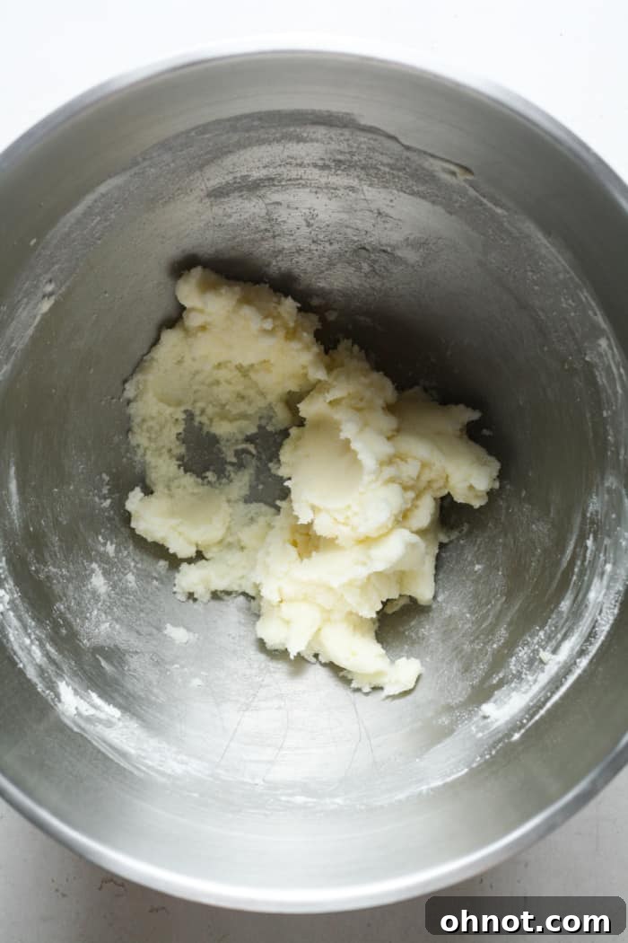 Creamy mixture of butter and white sugar in a stand mixer bowl, showing a smooth, light texture.