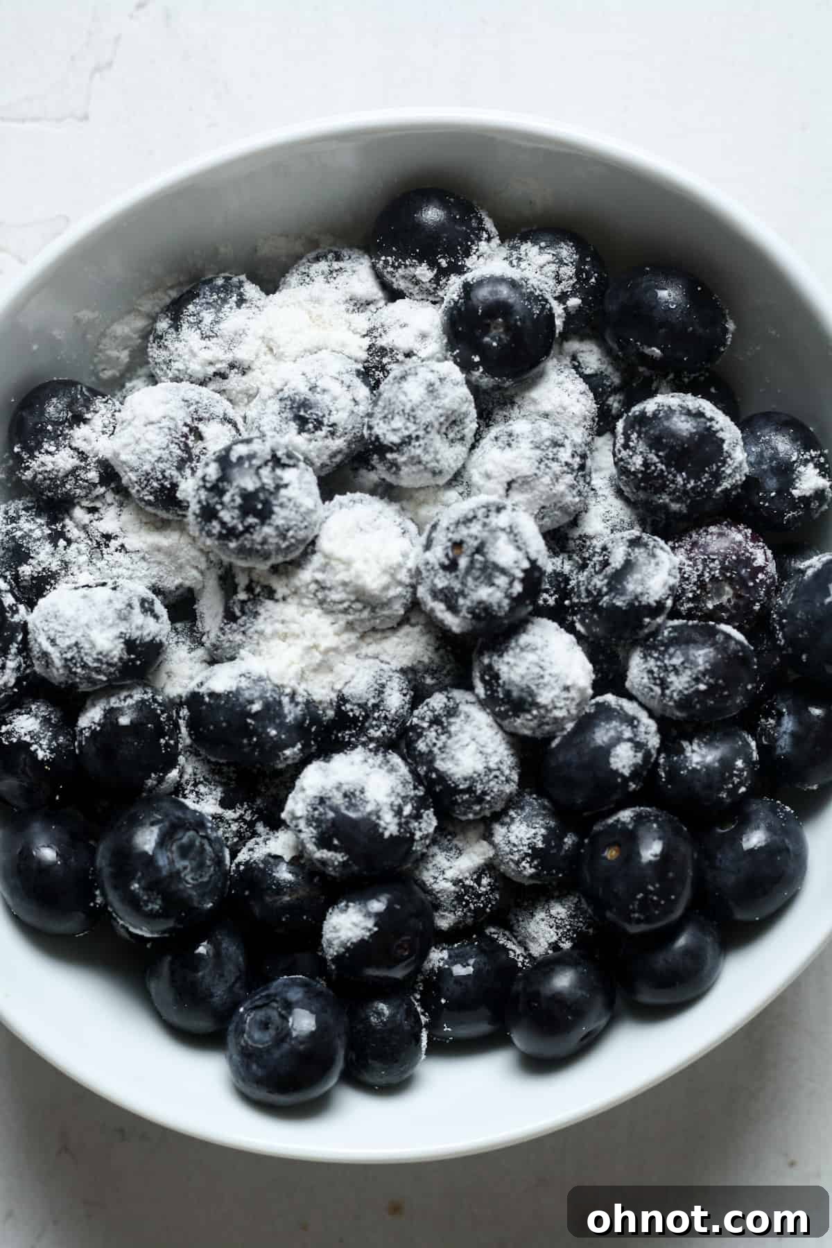 Fresh blueberries lightly coated with flour in a small bowl, ready to be added to the muffin batter.