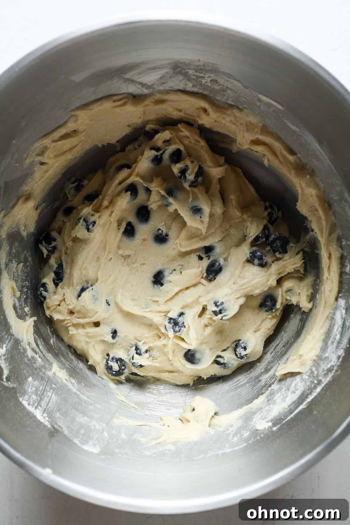 Blueberry muffin batter in a mixing bowl with fresh, floured blueberries gently folded in.