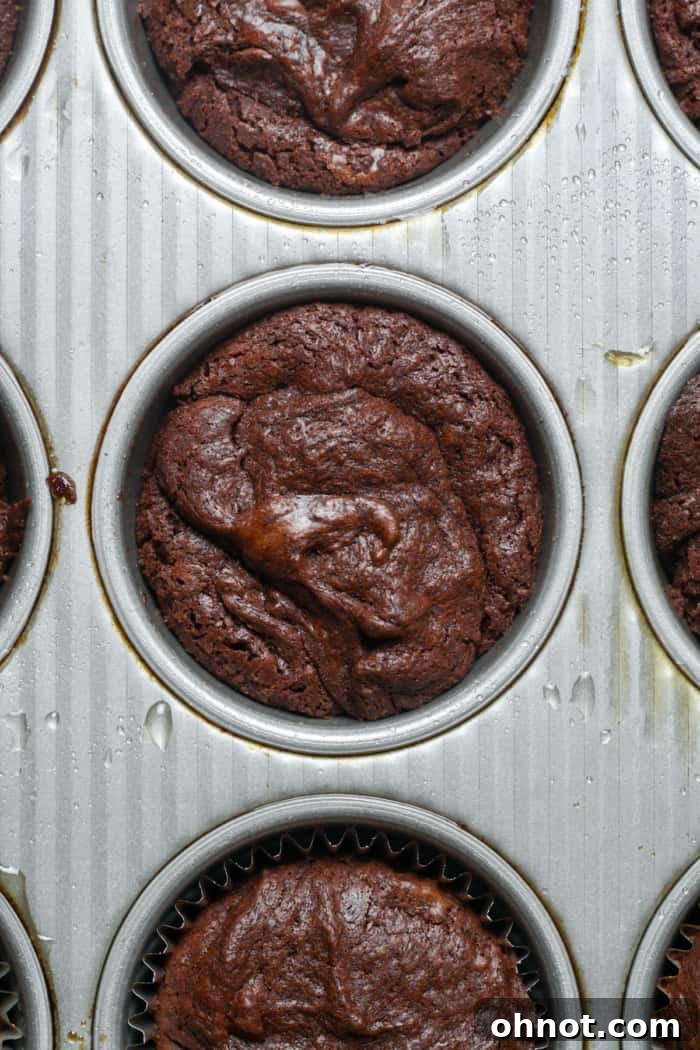 Freshly baked brownie bites cooling in a muffin pan.
