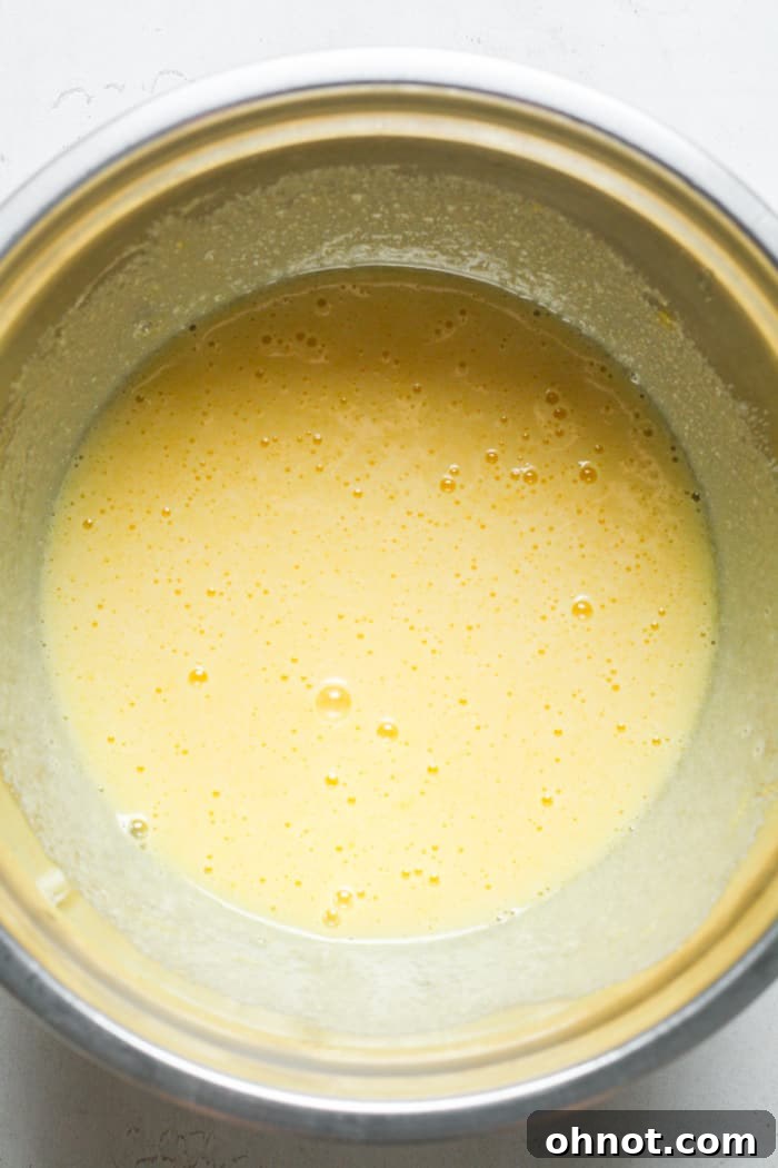 Creamy, whisked sugar and eggs in a mixing bowl.