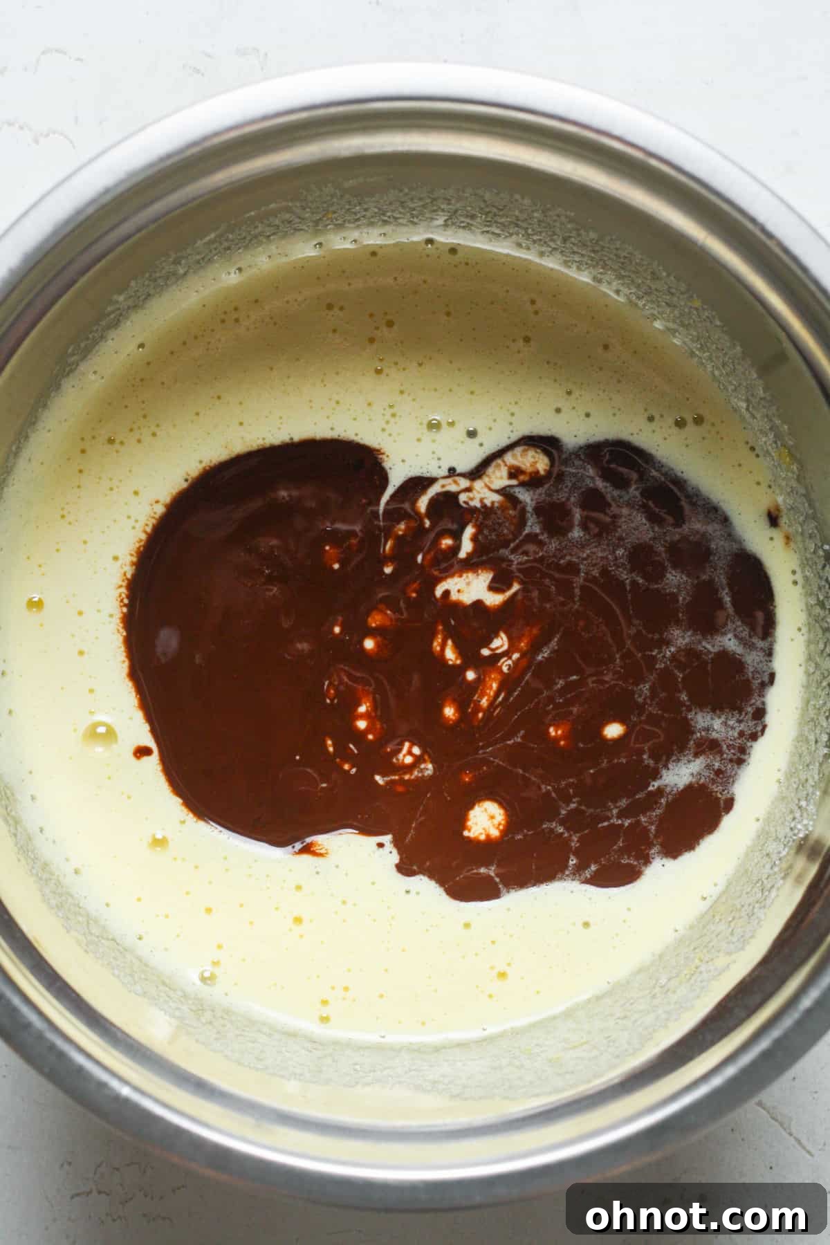 Melted chocolate mixture being poured into the sugar and egg blend.