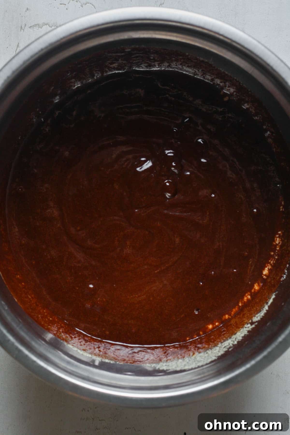 Bowl of smooth, glossy brownie batter after combining wet ingredients.