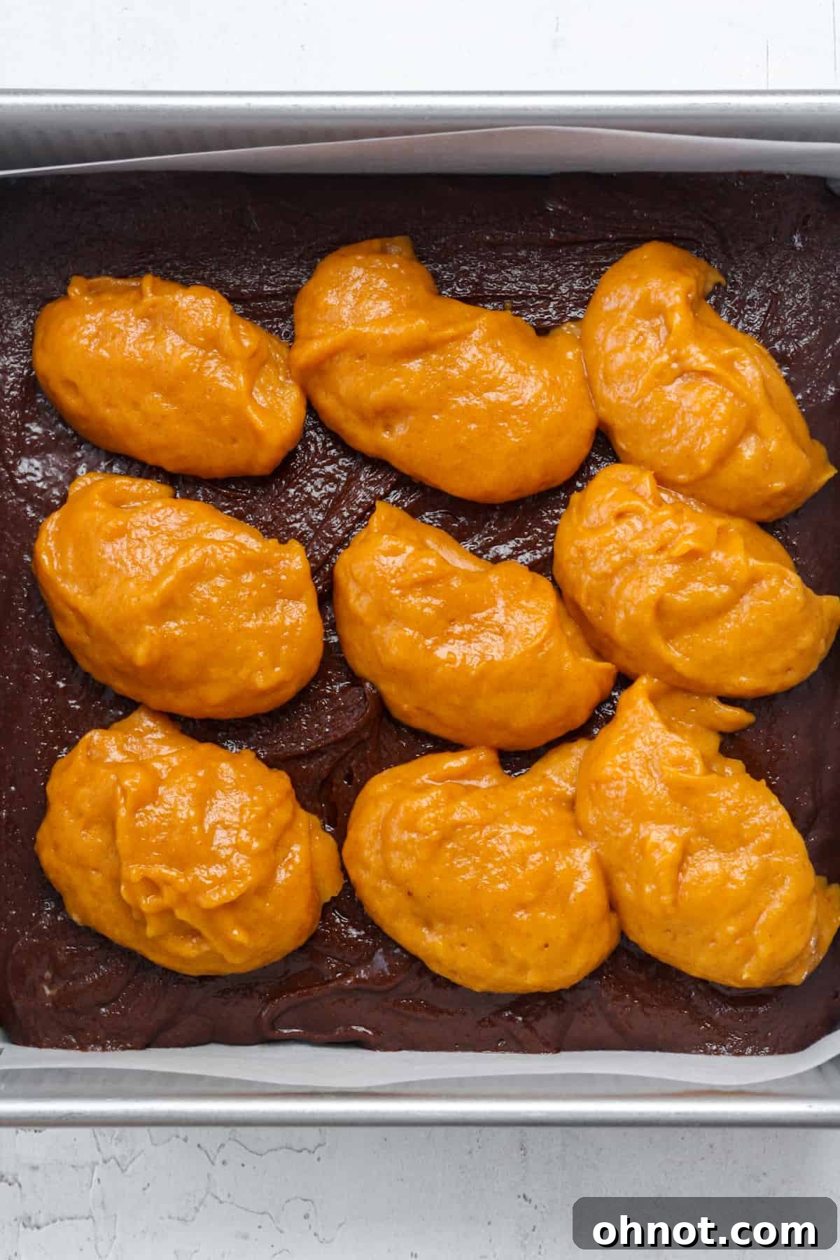 Dollops of pumpkin filling generously placed over the chocolate brownie batter.