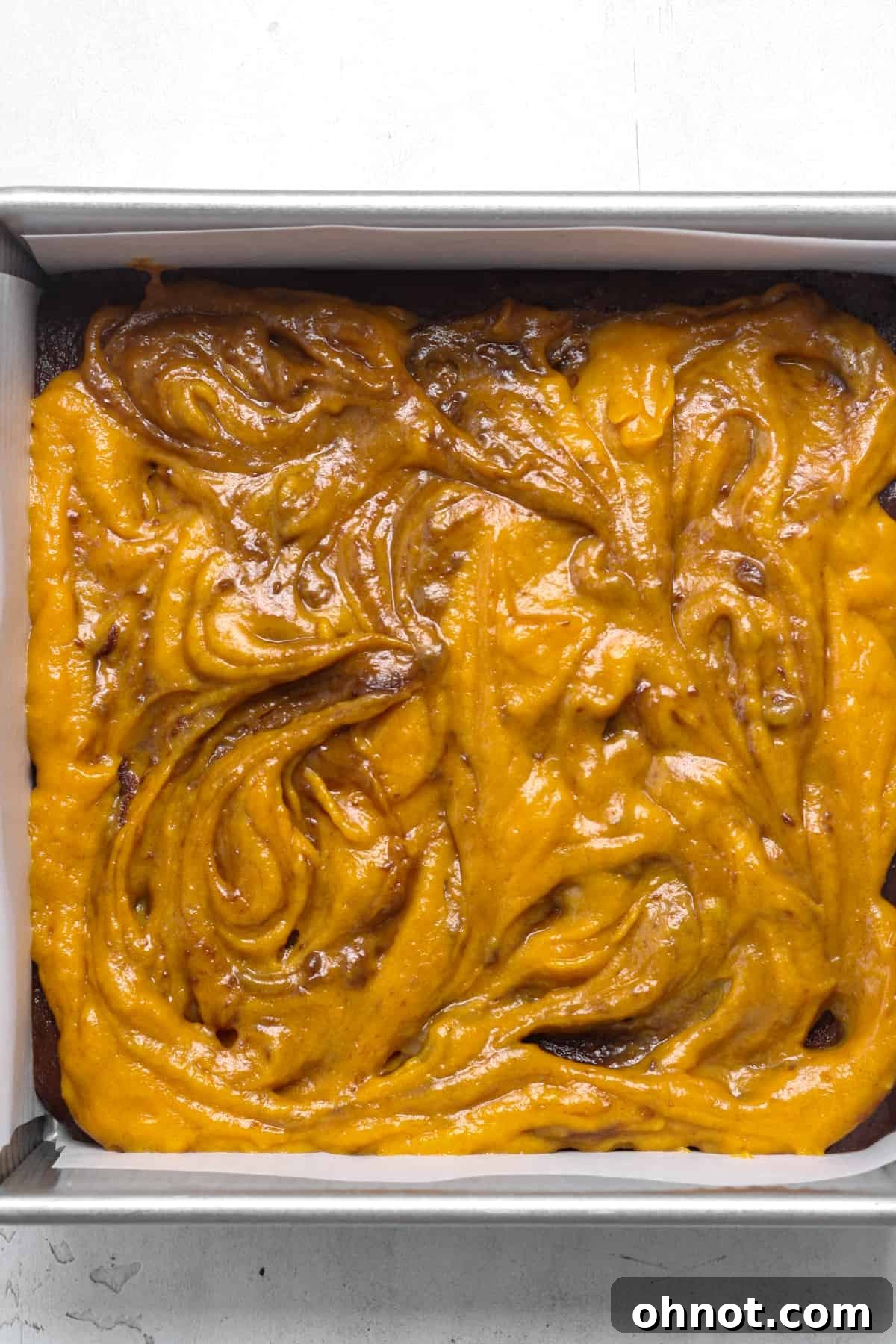 A knife creating a beautiful pumpkin swirl pattern in the batter.