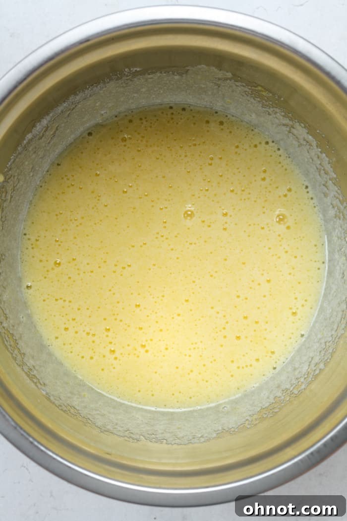 Eggs and sugar being whisked vigorously in a mixing bowl.