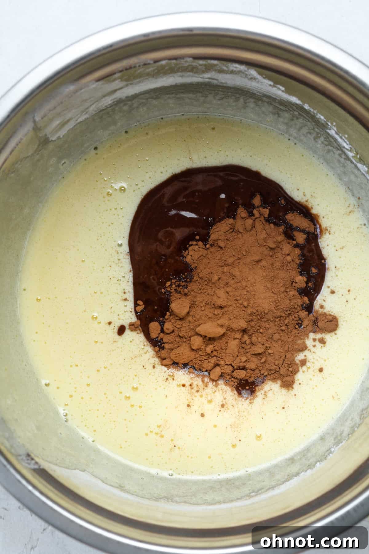 Cocoa powder and melted chocolate being added to batter.