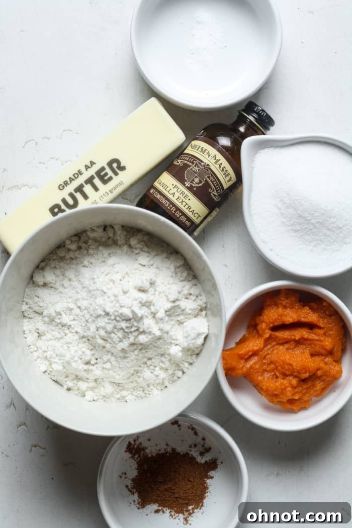 A selection of key ingredients for pumpkin sugar cookies, including pumpkin puree, flour, and butter.