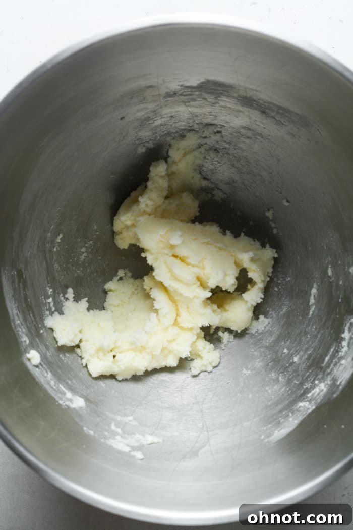 Cold butter and white granulated sugar being creamed together in a stand mixer bowl.