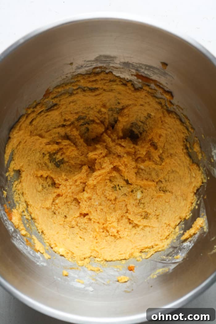 Orange-colored cookie batter with pumpkin puree and vanilla extract mixed in.