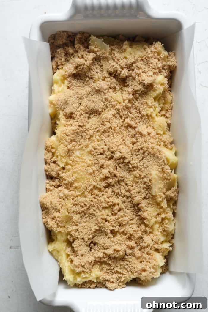 Raw apple bread batter with cinnamon sugar topping in the pan, ready for baking.