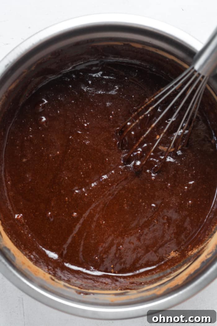 Rich chocolate brownie batter, made with almond flour, thoroughly mixed in a bowl and ready for the final additions before baking.