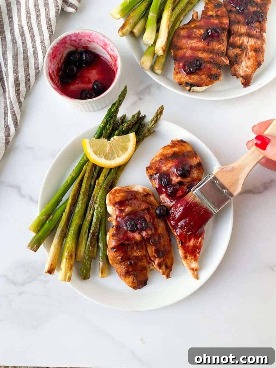 Plate of grilled blueberry BBQ chicken, garnished with fresh blueberries and parsley, ready to serve.