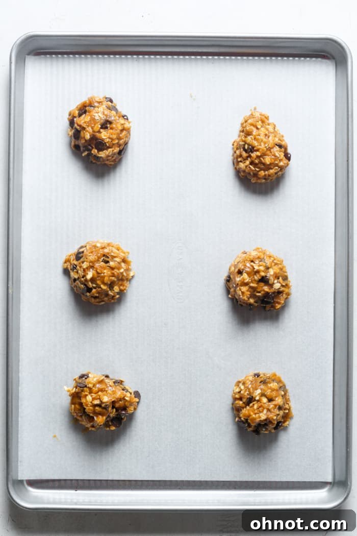 Six oatmeal cookie dough portions on a baking pan.