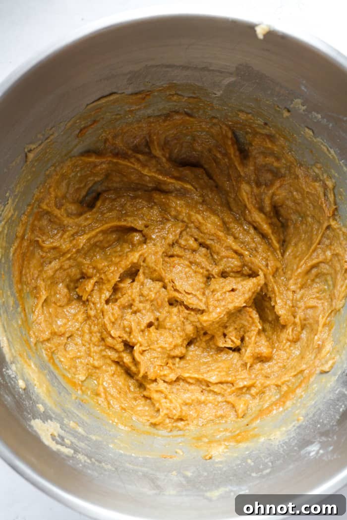 Creamy natural peanut butter being mixed into the cookie batter.