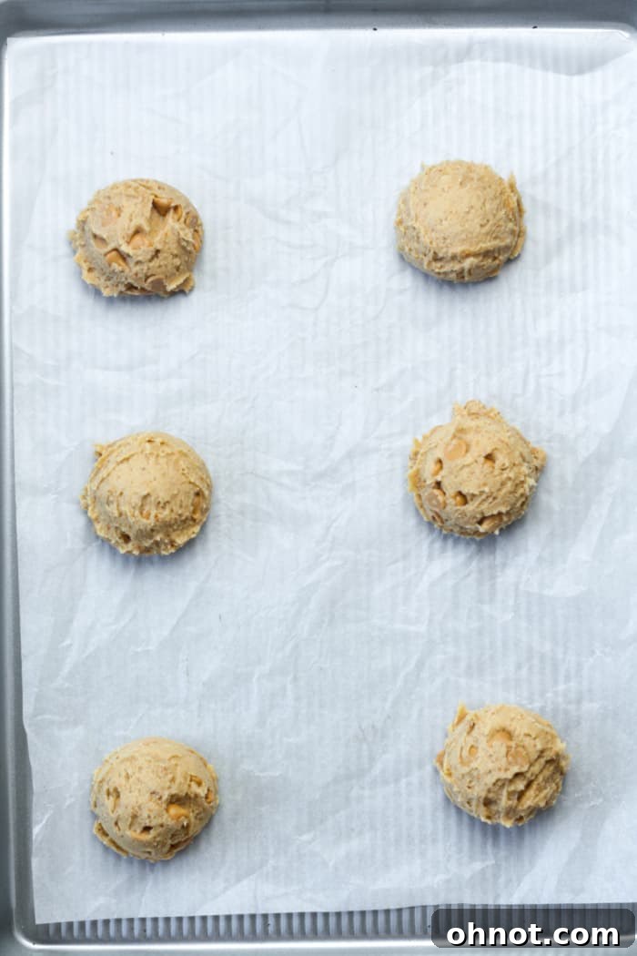Scooped balls of peanut butter cookie dough placed on a parchment-lined baking pan.