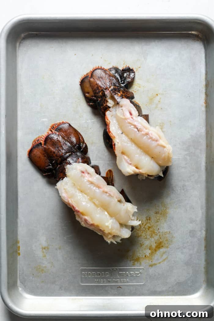 Butterflied lobster tails arranged on a baking pan