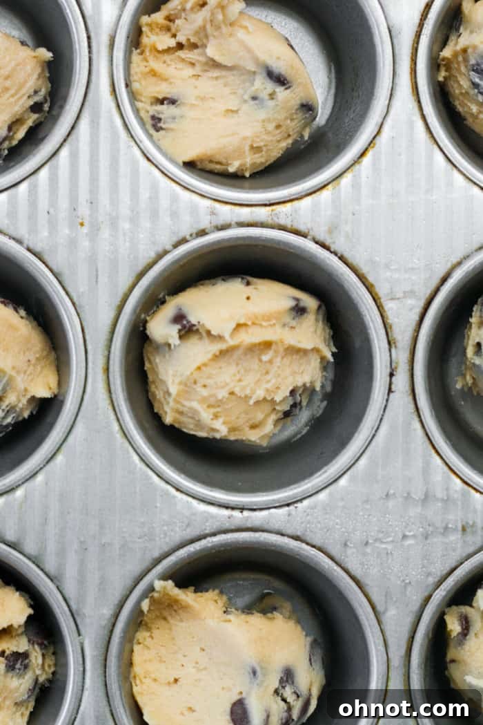Cookie dough scooped into muffin pan cavities.