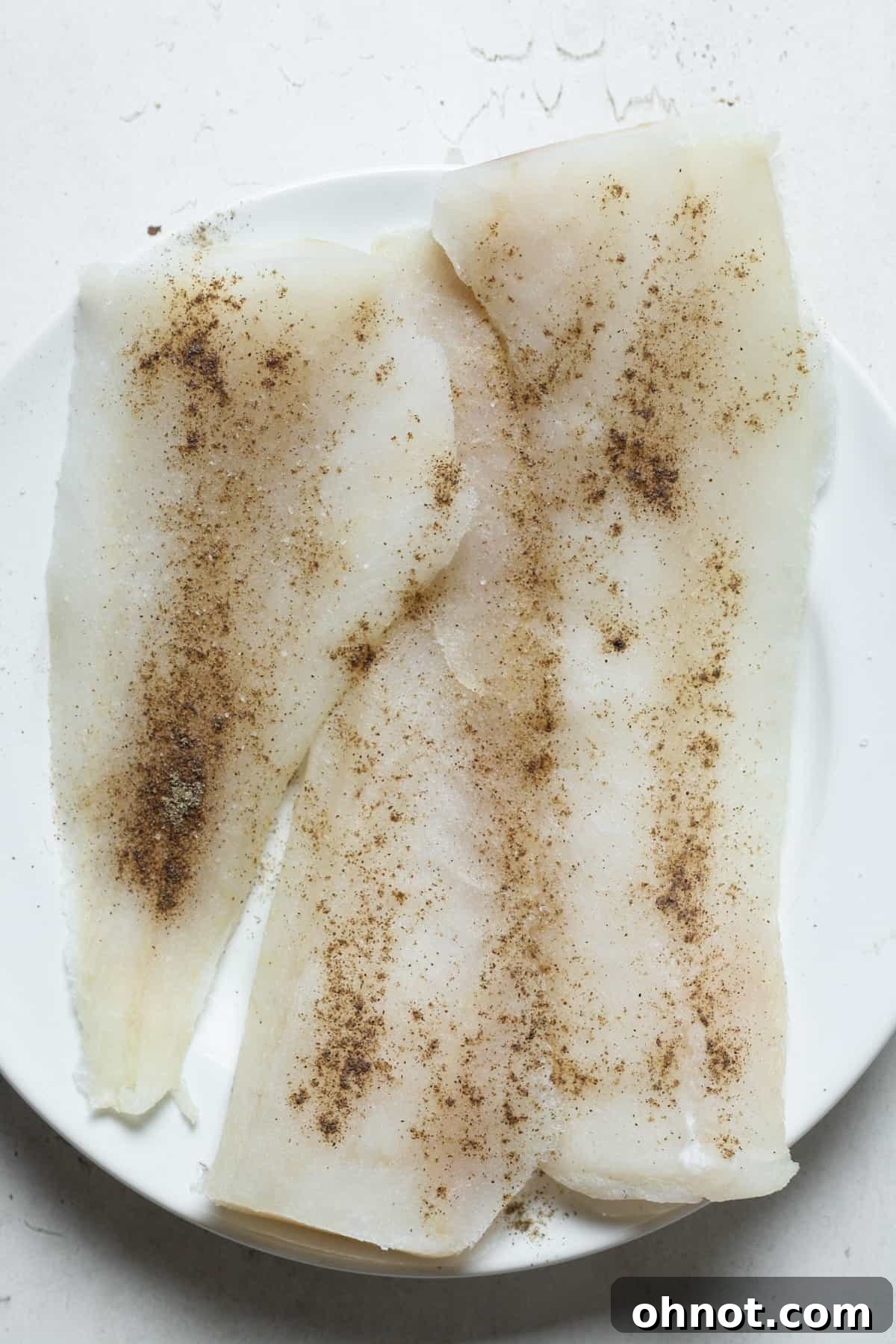 Seasoned haddock fillet on a plate.