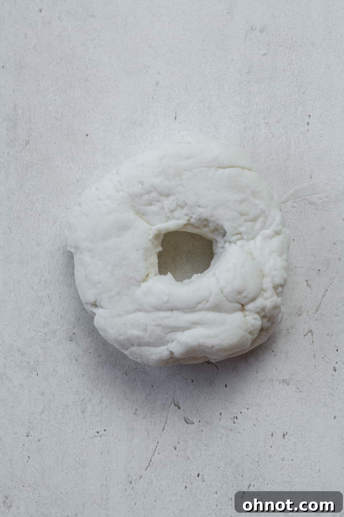 Raw bagel dough with a neatly formed hole.