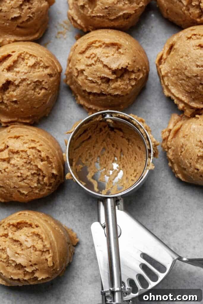 Almond butter balls neatly arranged on a parchment-lined baking sheet, ready for the freezer.
